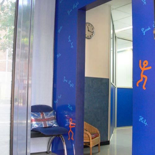 Entrada a aula amb parets en colors blau elèctric i taronja