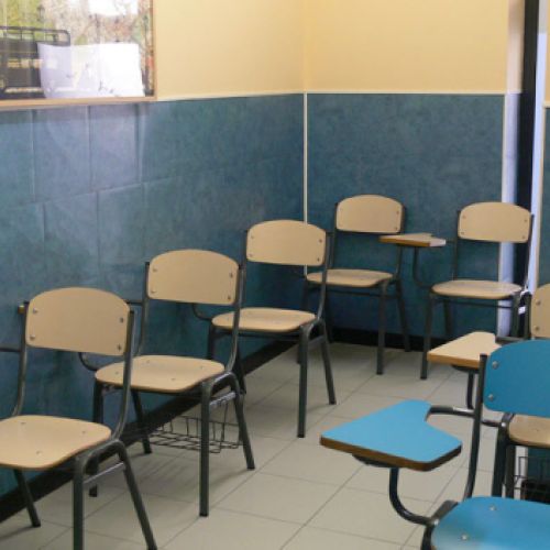 Interior d'aula amb pupitres de color blau i taronja clar