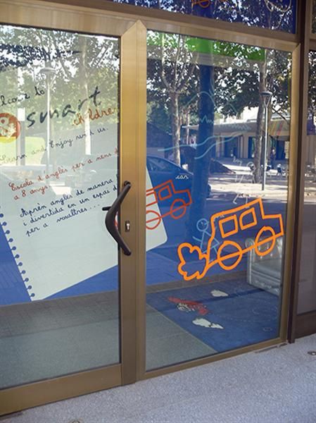 Foto de porta amb vinils de dibuixos infantils de cotxes i paret amb dibuix de fulla de quadern