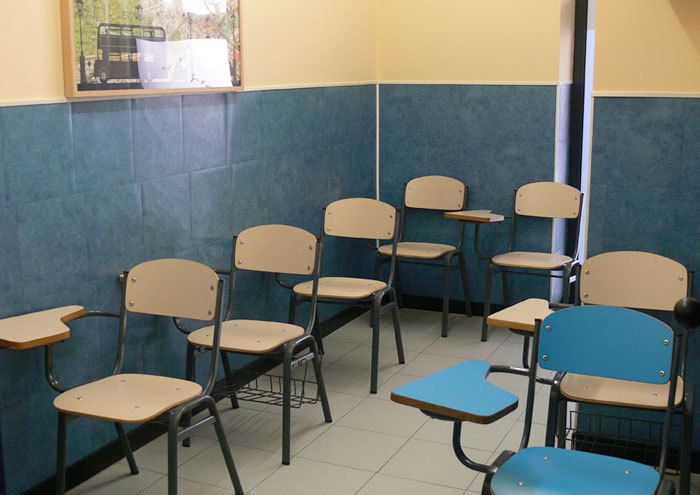 Interior d'aula amb pupitres de color blau i taronja clar