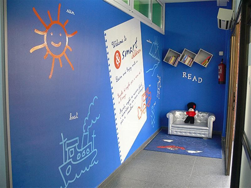 Imagen de interior de academia de Smart children con paredes de color azul, dibujos infantiles y muñeco de guardia inglés