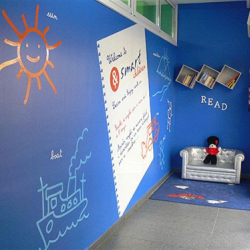 Imatge d´interior d´acadèmia de Smart children amb parets de color blau, dibuixos infantils i ninot de guàrdia anglès