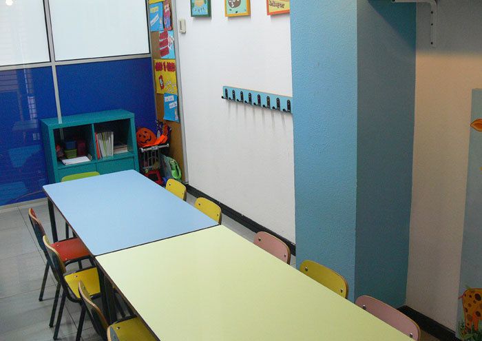 Interior de aula infantil con mesas y  sillas pequeñas de colores
