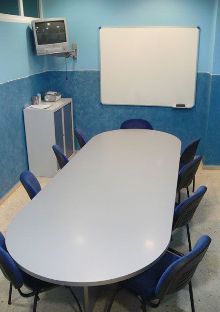 Interior de aula con paredes de color azul y mesa grande ovalada en el centro