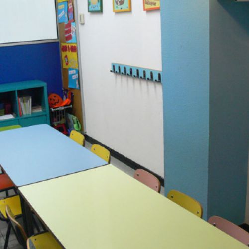 Interior d´aula infantil amb taules i cadires petites de colors