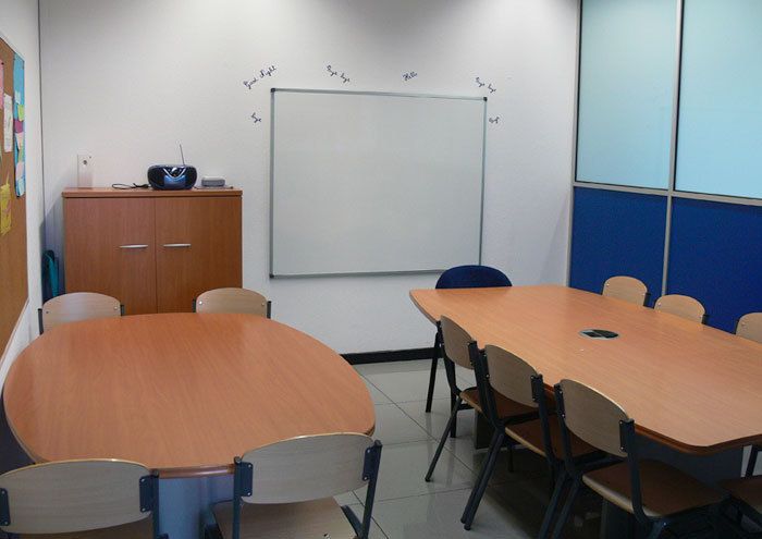 Interior de aula con dos mesas grandes y sillas a los lados