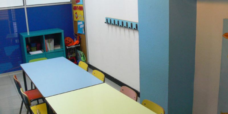 Interior d´aula infantil amb taules i cadires petites de colors